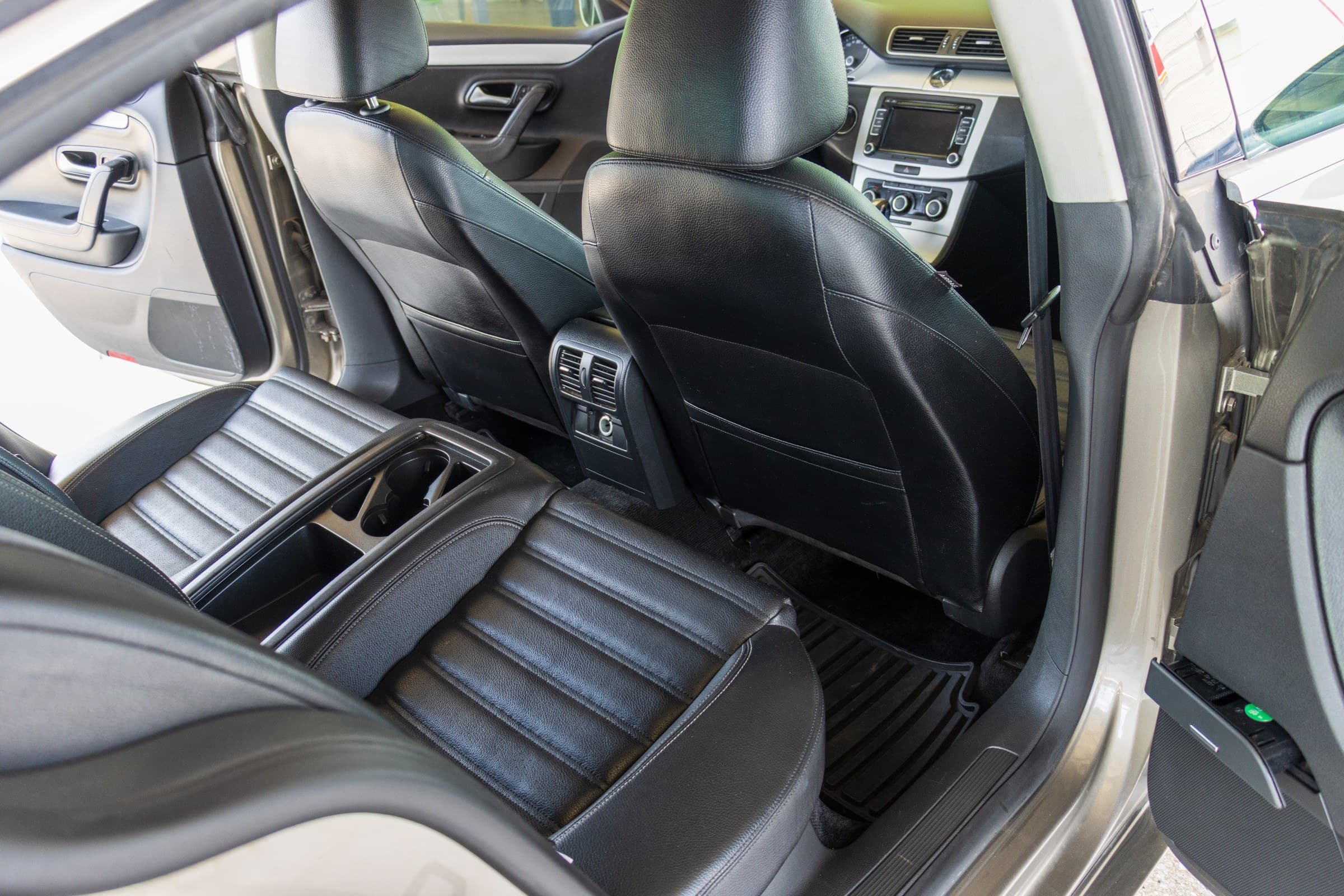 Rear cabin of the CC seen through the open passenger door, showing its two black leather rear bucket seats.