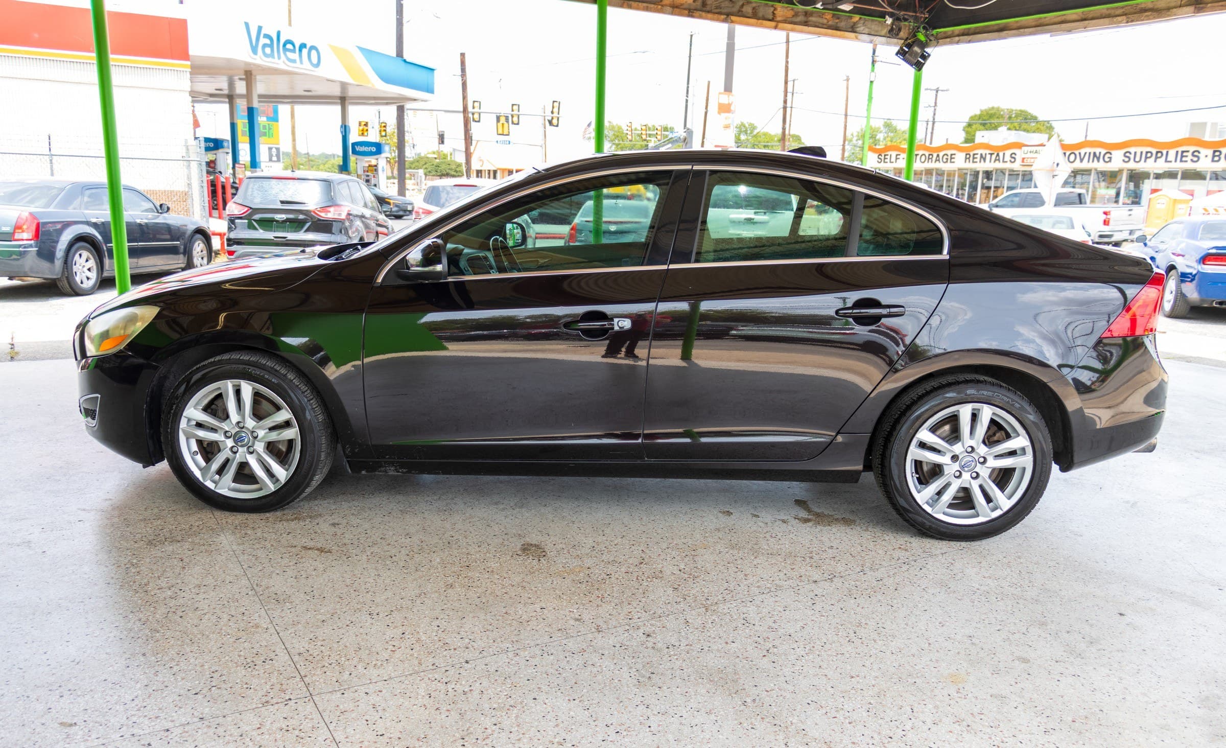 Full driver-side profile of the black Volvo S60, showing its silver five-spoke alloy wheels.