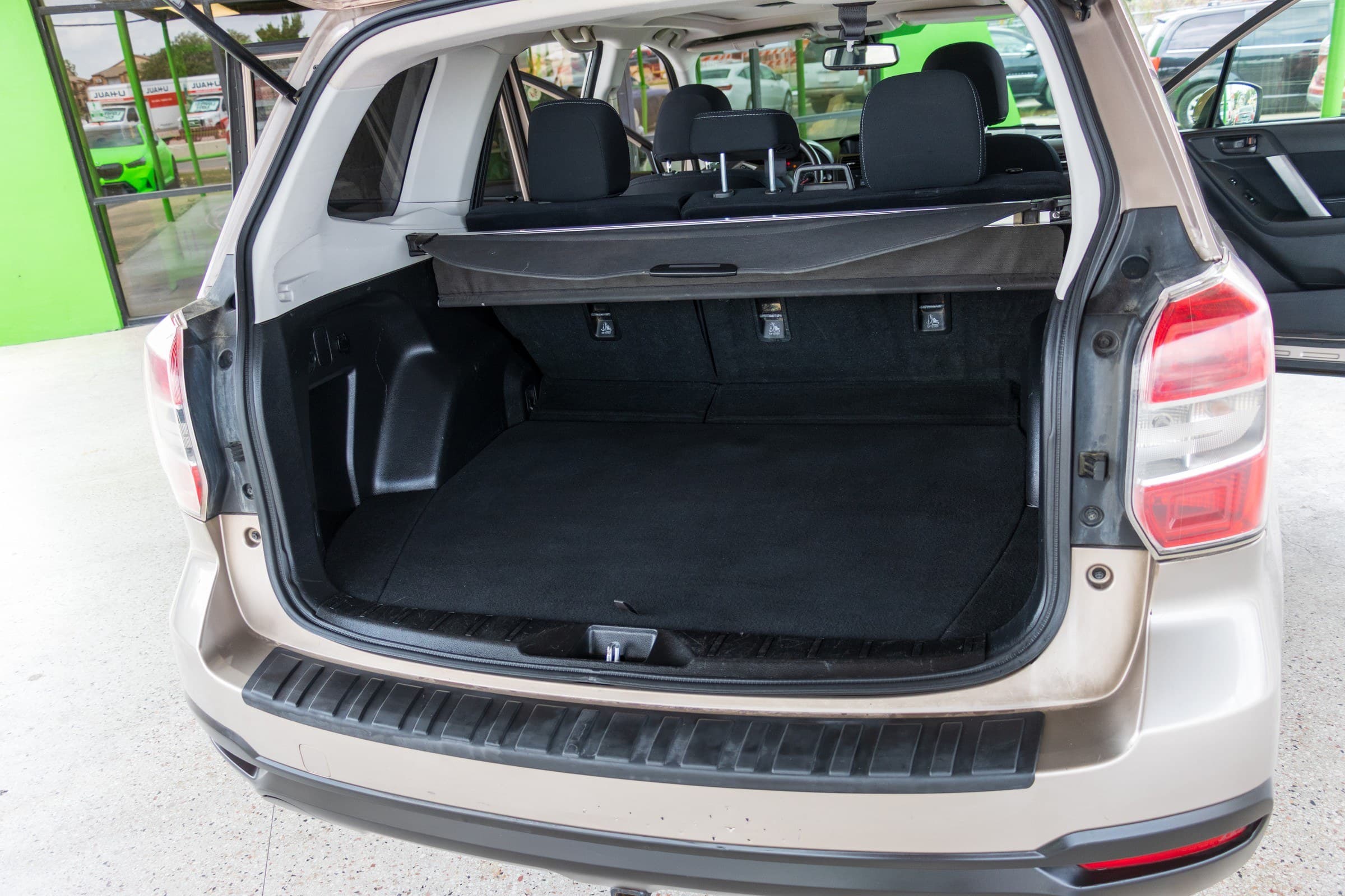 The Forester's carpeted cargo area with the tailgate open and the retractable cargo cover in place behind the rear seats.