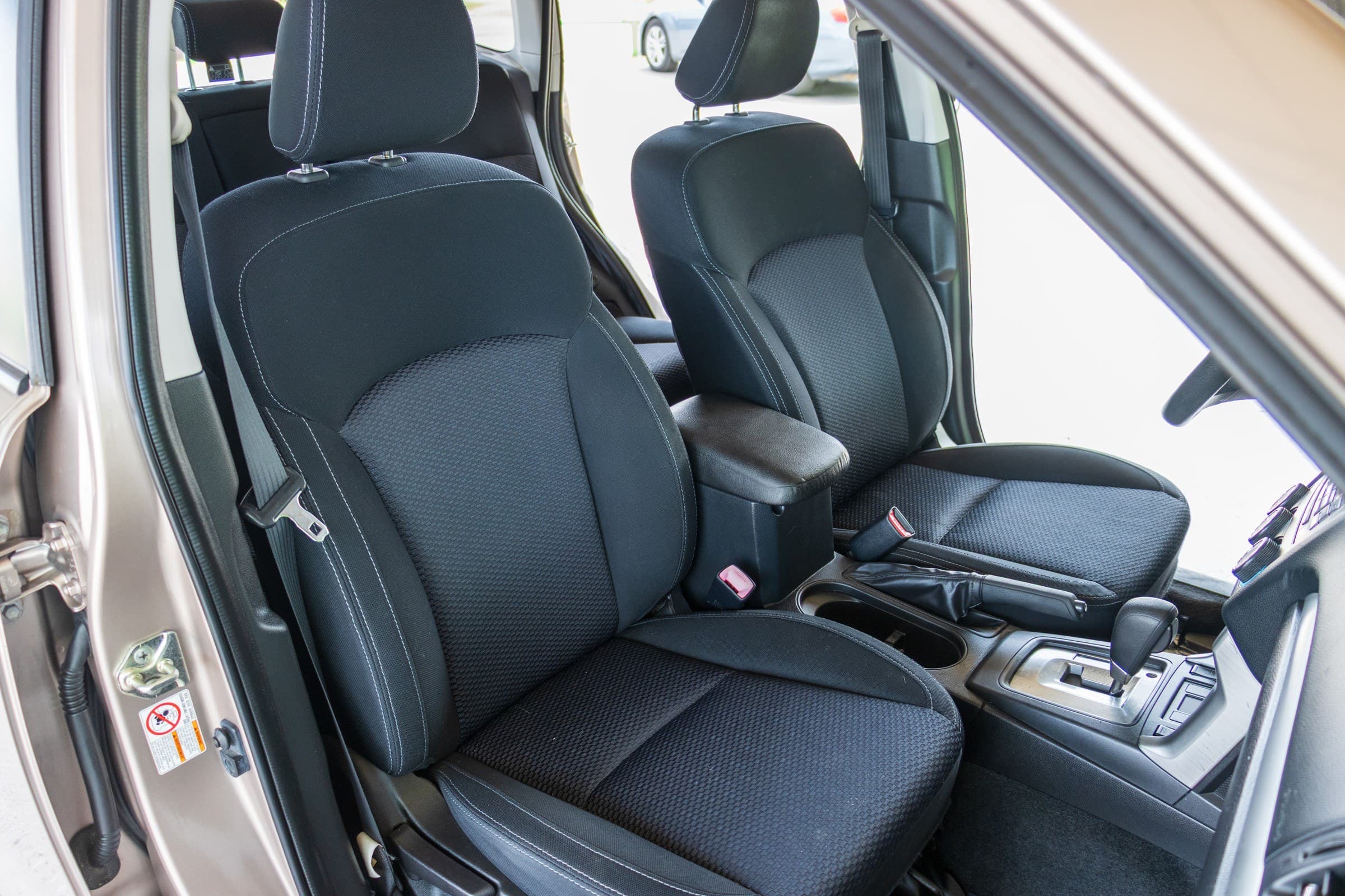 The Forester's black cloth front seats and centre console, seen through the open driver's door.