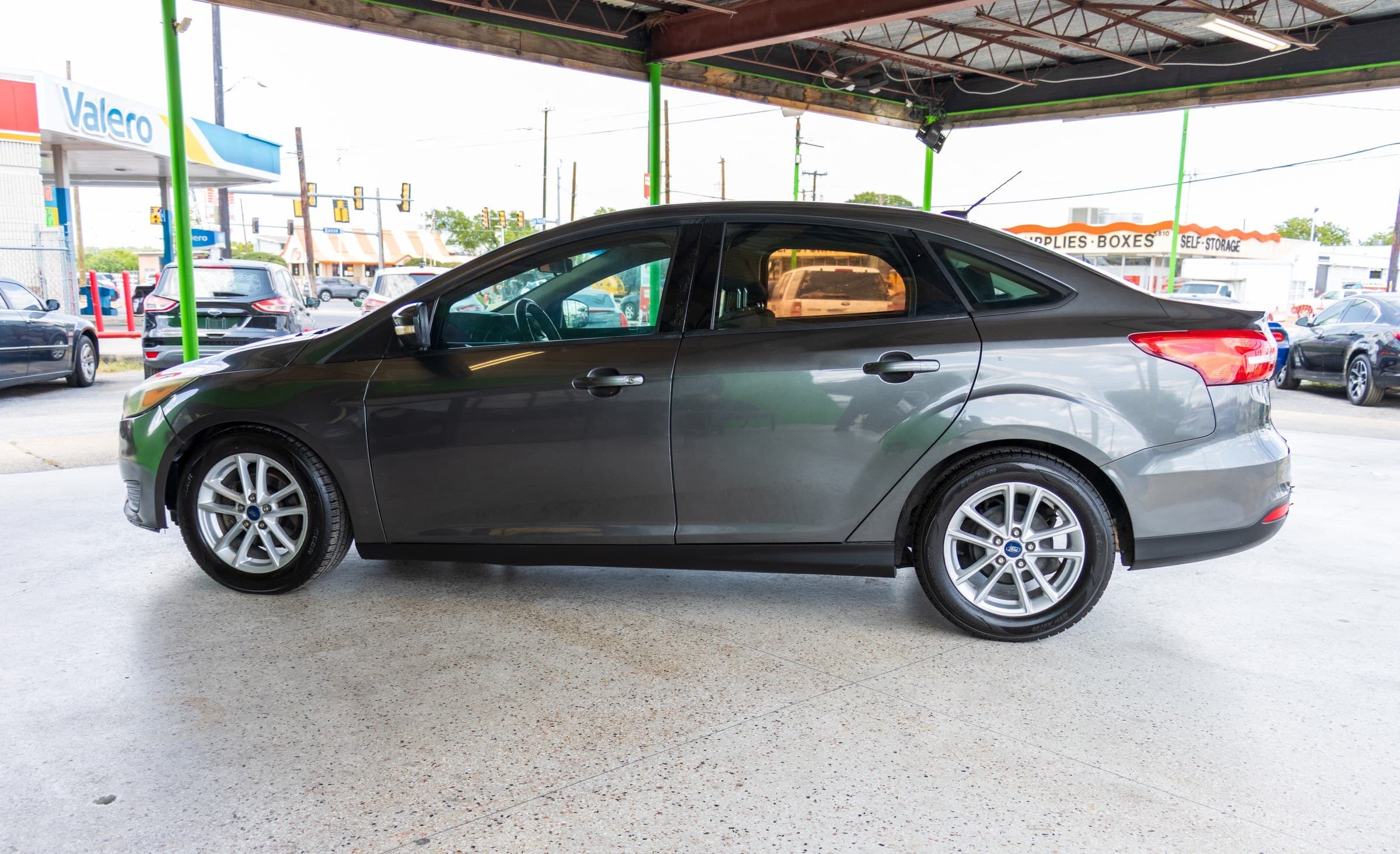 Full driver-side profile of the gray Ford Focus, showing its five-spoke silver alloy wheels.