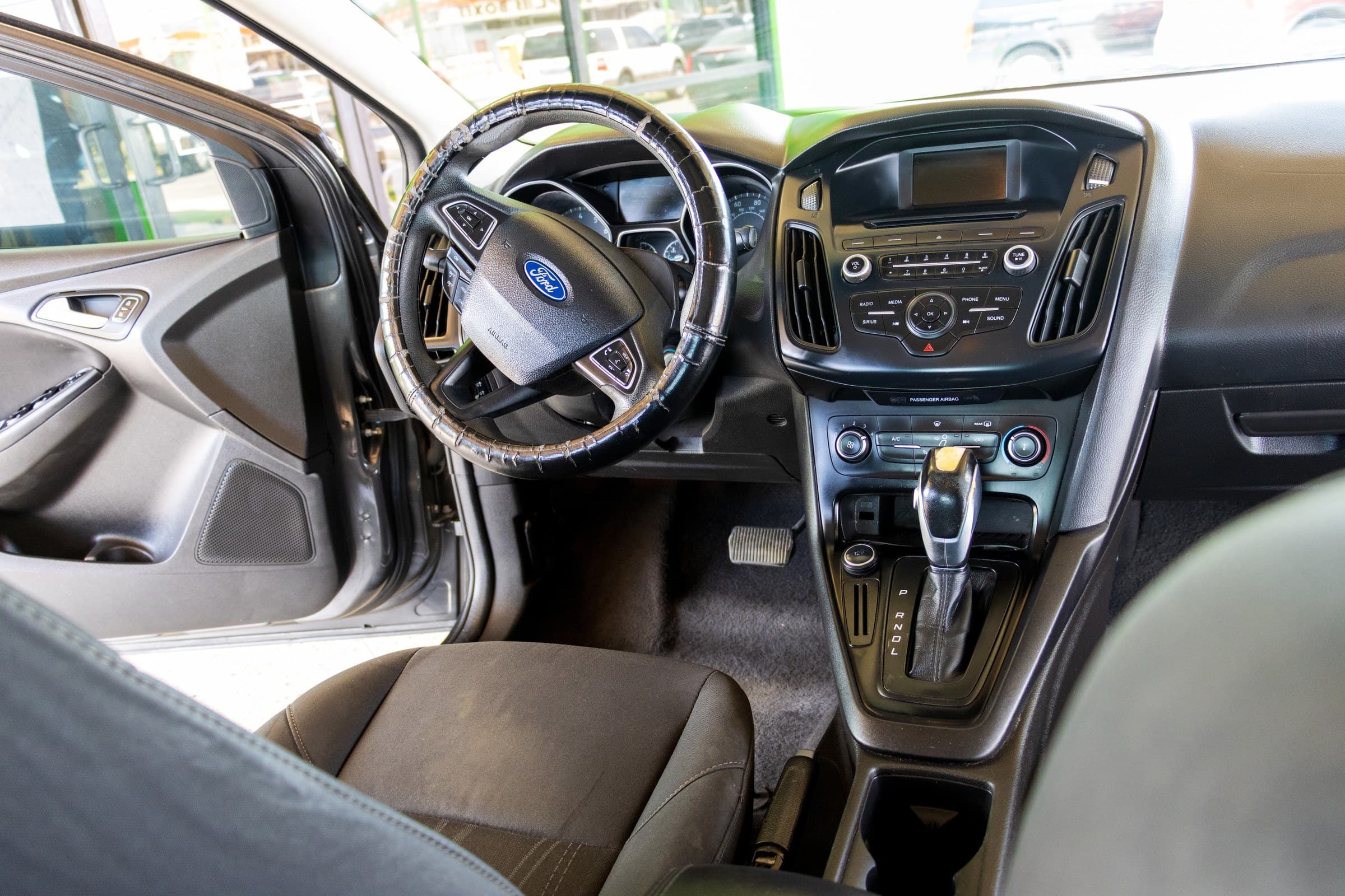 The Focus's dashboard seen through the open driver's door, with the centre stack radio, climate dials and automatic shifter.