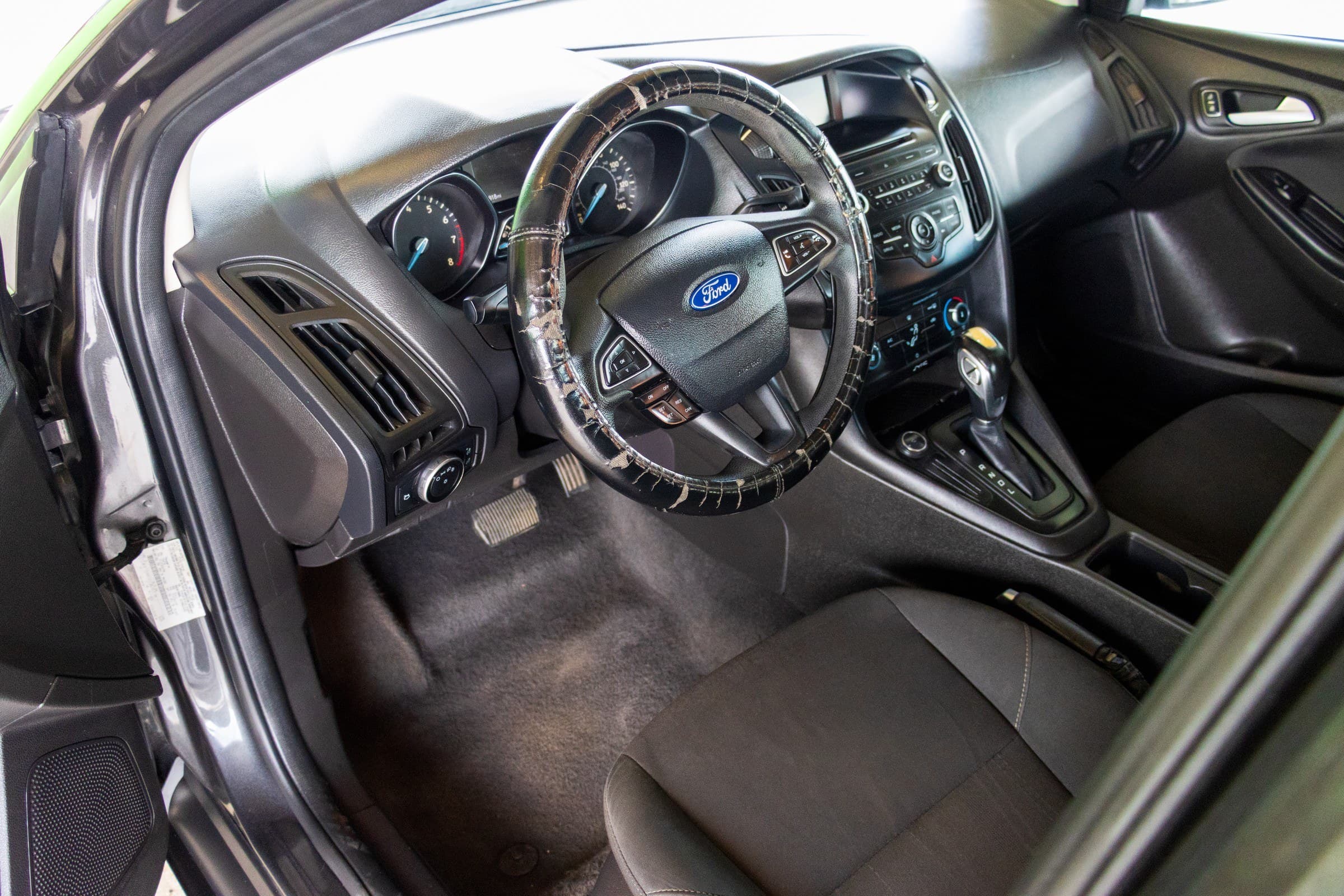 Driver's cockpit of the Focus, with the instrument cluster behind a steering wheel wearing an aftermarket cover.