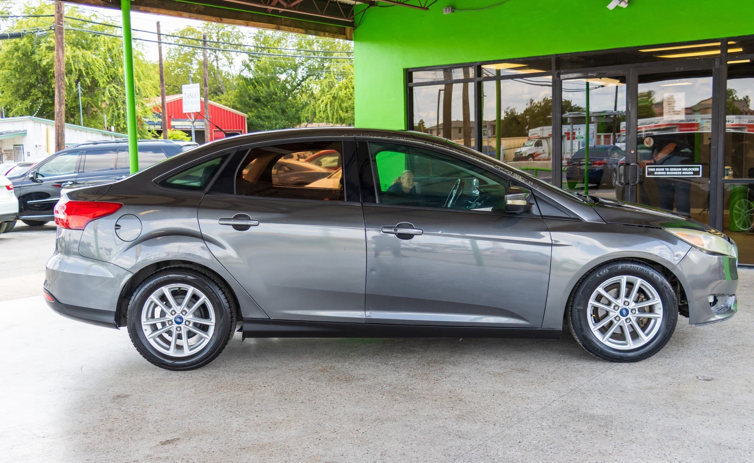 Full passenger-side profile of the gray Ford Focus parked under the Kelley Autoplex canopy.