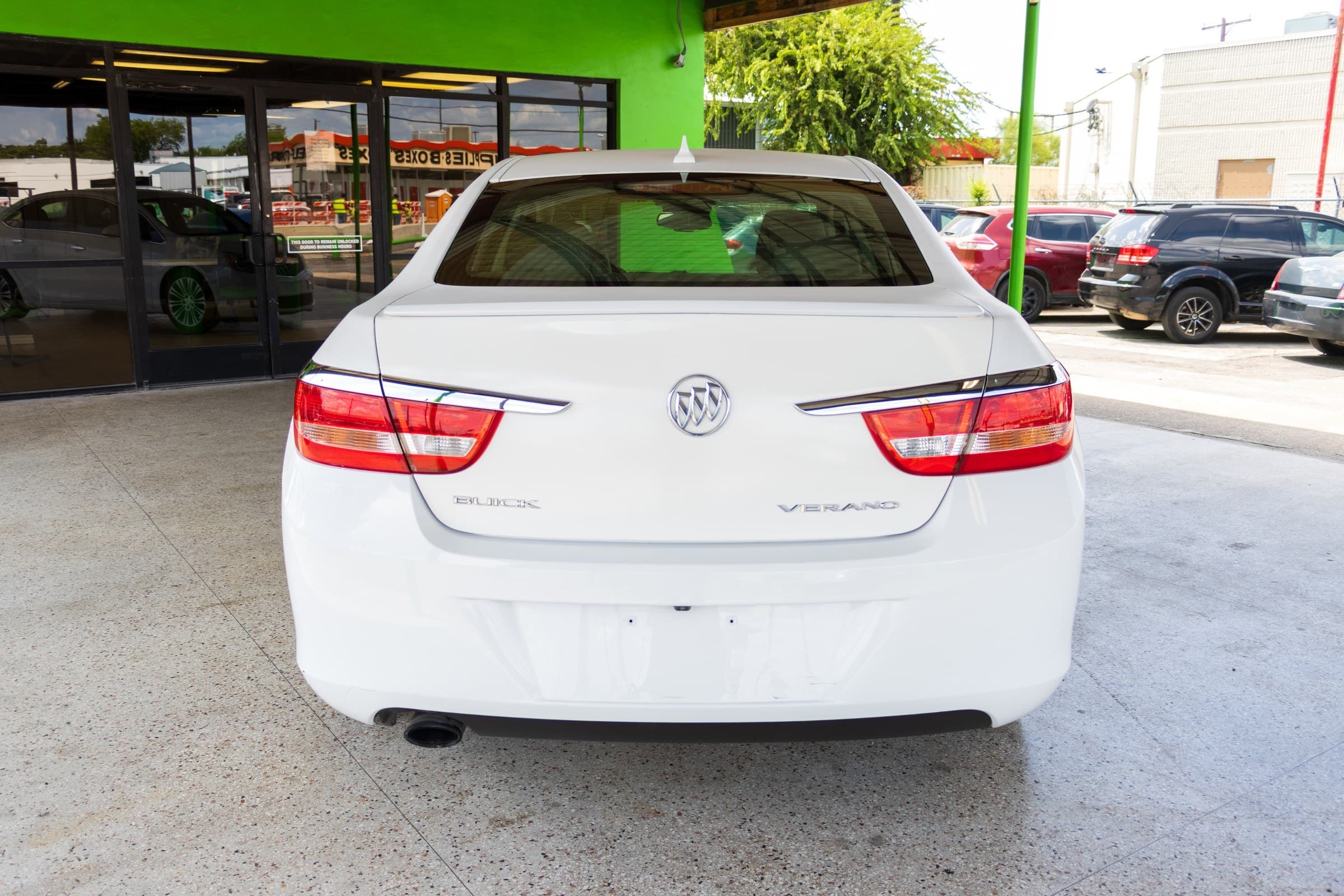 Rear view of the white Verano, showing the chrome trim strip, Buick badge and Verano lettering on the trunk.